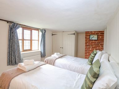 A bedroom with two single beds blue curtains and a built in wardrobe at Manor Farm House in Bacton