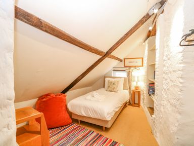 A small attic bedroom with a single bed bedside table lamp and built in shelves at Manor Farm House in Bacton
