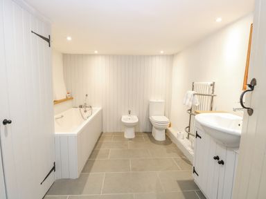 A bathroom with a bathtub bidet toilet towel radiator and sink at Manor Farm House in Bacton