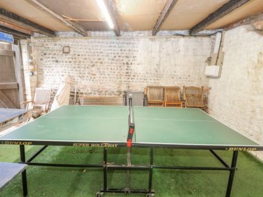 An indoor room with a Dunlop Super Rollaway table tennis table chairs and a wooden door at Manor Farm House in Bacton