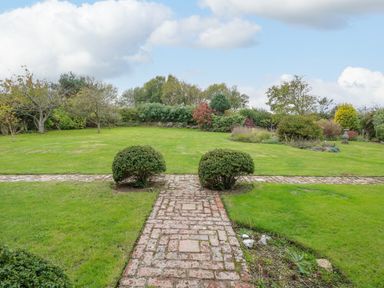 A garden with a brick pathway and shrubs at Manor Farm House in Bacton