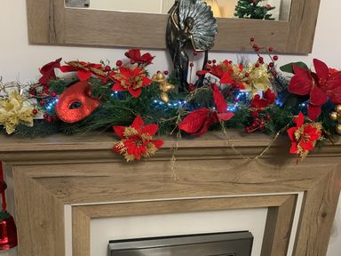 A fireplace mantle with red and gold floral decorations and blue lights at Lilac Lodge in Carnforth