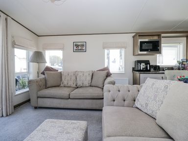 A living room with a sofa and a microwave at Lilac Lodge in Carnforth