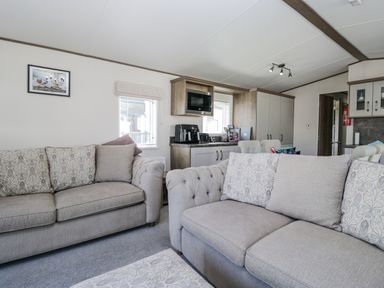 A living room with sofas and a television at Lilac Lodge in Carnforth