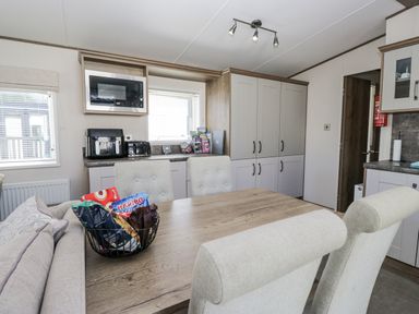 A kitchen with appliances and dining area at Lilac Lodge Carnforth