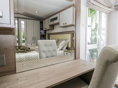 A bedroom with a bed and dresser at Lilac Lodge Carnforth