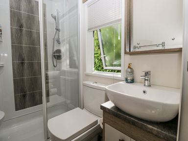 A bathroom featuring a shower, toilet, and sink at Lilac Lodge in Carnforth