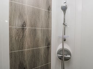 A shower area with a showerhead and tiled wall at Lilac Lodge in Carnforth