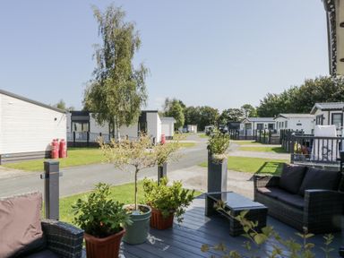 An outdoor area with seating and caravans at Lilac Lodge in Carnforth