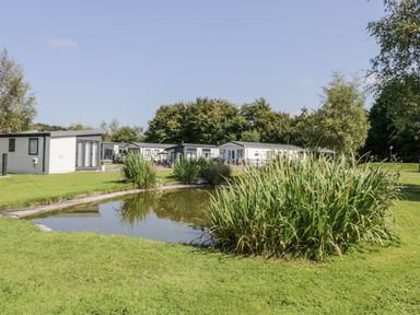 An outdoor area with holiday lodges and a pond at Lilac Lodge in Carnforth