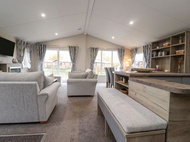 An open plan living room and kitchen area with sofas dining table and built in shelves at Fountain View in Warton near Carnforth