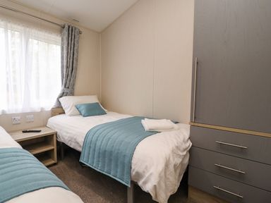 A bedroom with two single beds a bedside table remote control and a wardrobe at Fountain View in Warton near Carnforth