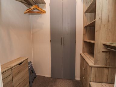 A walk-in closet with wooden shelves drawers hangers and a gray cabinet at Fountain View in Warton near Carnforth