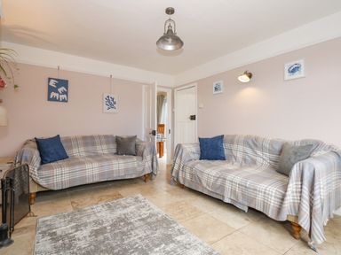 A living room with two sofas covered with plaid fabric and cushions at Beck View in Sheringham
