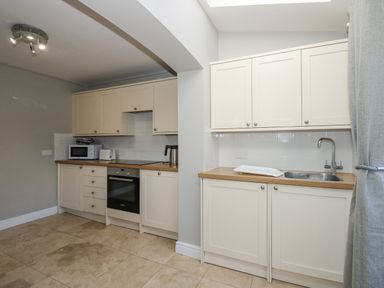 A kitchen with cream cabinets a microwave toaster kettle and sink at Beck View in Sheringham