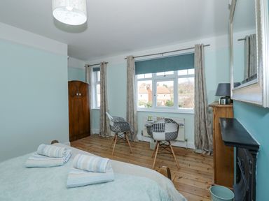 A bedroom with bed towels two chairs a wooden wardrobe and a window at Beck View in Sheringham