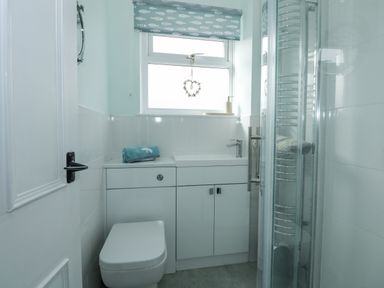 A bathroom with a toilet sink shower and a window with a fish patterned blind at Beck View in Sheringham