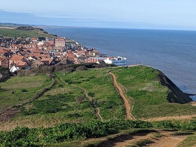 A coastal town with red-roofed houses near green hills and the ocean at Beck View in Sheringham