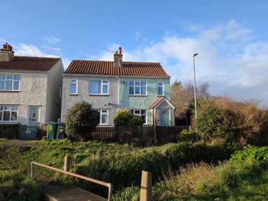 A semi detached house with a tiled roof and front garden in Sheringham