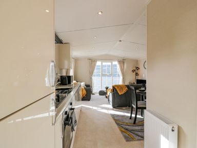 An open kitchen leading to a living room with grey sofas and a dining table at 11 Mansion View in Helensburgh near Kilcreggan