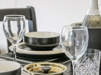 A dining table with stacked bowls and plates wine glasses and a bottle in an ice bucket at 11 Mansion View in Helensburgh near Kilcreggan