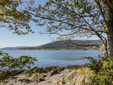 A coastal view with water rocky shore trees and hills in the distance at 11 Mansion View Helensburgh near Kilcreggan