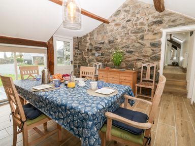A dining room with a set table and stone wall at Y Bwthyn in Dyffryn Ardudwy