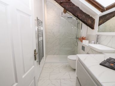 A bathroom with a shower enclosure a toilet a sink and a towel at Y Bwthyn in Dyffryn Ardudwy
