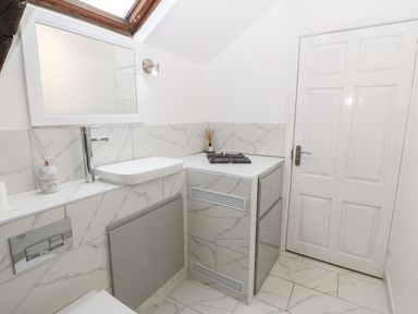 A bathroom with a wall-mounted sink mirror and a closed white door at Y Bwthyn in Dyffryn Ardudwy
