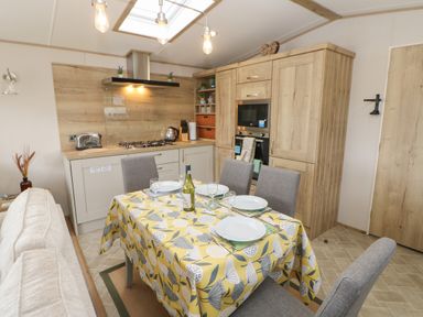 A kitchen and dining area with a table set for four a stove toaster and built in oven at 10 Cheviot View Haggerston near Lowick