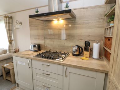 A kitchen countertop with a gas stove kettle toaster knife block and paper towel holder at 10 Cheviot View in Haggerston near Lowick