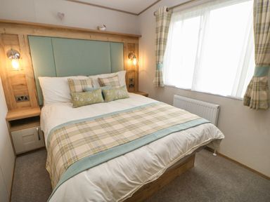 A bedroom with a double bed and plaid bedding and curtains at 10 Cheviot View in Haggerston near Lowick