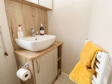 A bathroom sink with soap dispensers on a wooden cabinet and a towel on a white radiator at 10 Cheviot View in Haggerston near Lowick