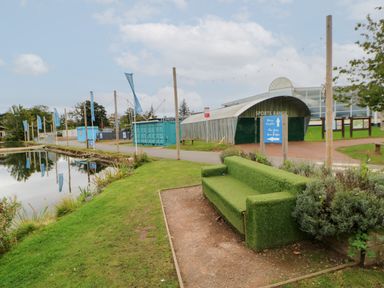 An outdoor sports range next to a pond with a green grass covered bench and signs at 10 Cheviot View in Haggerston near Lowick