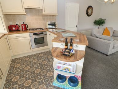A kitchen with wooden countertops and patterned floor next to a living room with a gray sofa at Mildred's Lodge in Felton