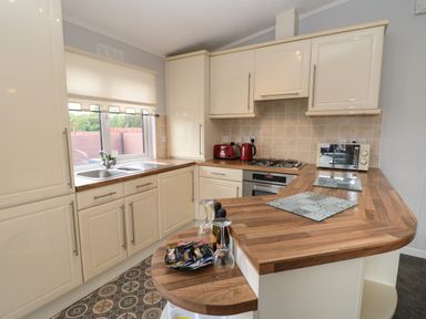 A kitchen with cream cabinets wooden countertops a double sink and appliances at Mildred's Lodge in Felton
