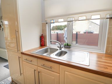 A kitchen sink with a faucet on a wooden countertop under a window with a fire extinguisher on the side Mildred's Lodge Felton