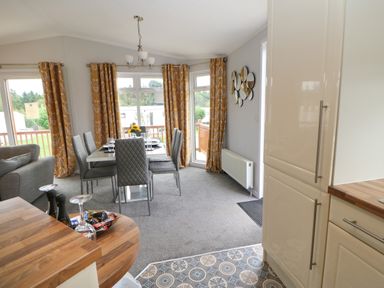 A dining area with gray chairs and a table near windows with yellow curtains and a kitchen counter with wooden top at Mildred's Lodge in Felton