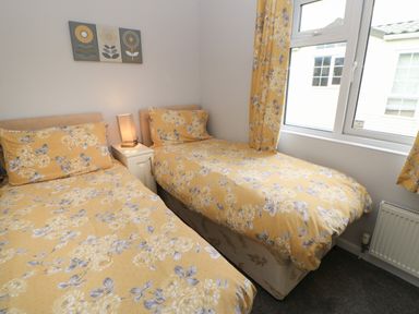 A bedroom with two single beds and yellow floral bedding at Mildred's Lodge in Felton