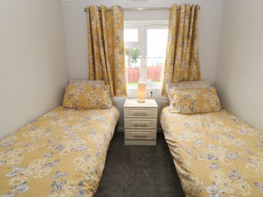 A bedroom with two single beds with floral bedding and matching curtains at Mildred's Lodge in Felton