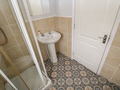 A bathroom with a shower enclosure a pedestal sink and a white door at Mildred's Lodge in Felton