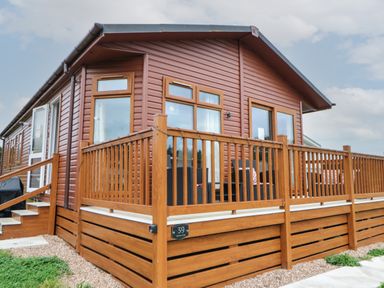 Exterior of a brown wooden lodge with a fenced porch and outdoor seating at Mildred's Lodge in Felton