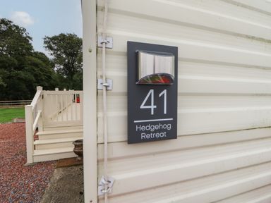 A close up of a sign with number 41 and Hedgehog Retreat on the side of a beige building with steps and railing leading to a door outside at Hedgehog Retreat in Felton