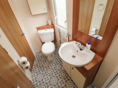 A bathroom with a toilet sink mirror towel rack and patterned floor at Hedgehog Retreat in Felton