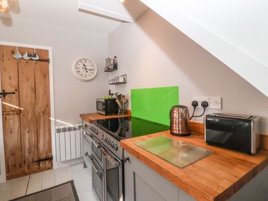 A kitchen with a wooden countertop stove kettle toaster and microwave at Secret Cottage Southwold