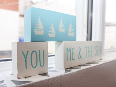 Decorative wooden blocks on a windowsill with text saying you me and the sea and sailboat images at Secret Cottage in Southwold