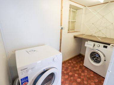 A laundry room with a washing machine and a dryer on a tiled floor at 6 Calgarth View in Windermere