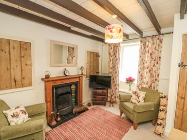 A sitting room with two armchairs a fireplace a television and floral curtains at 12 Castlegate in Pickering