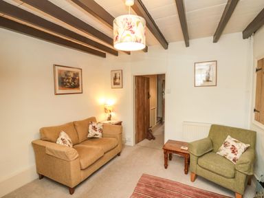 A living room with a brown sofa and green armchair and wooden beams on the ceiling at 12 Castlegate in Pickering