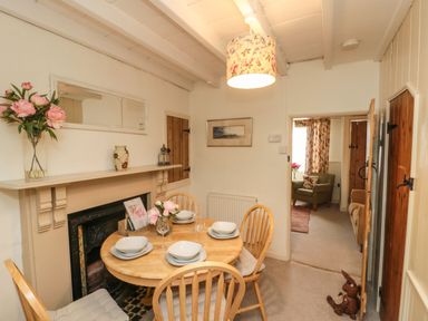 A dining area with a round wooden table set for four and a floral lampshade at 12 Castlegate in Pickering